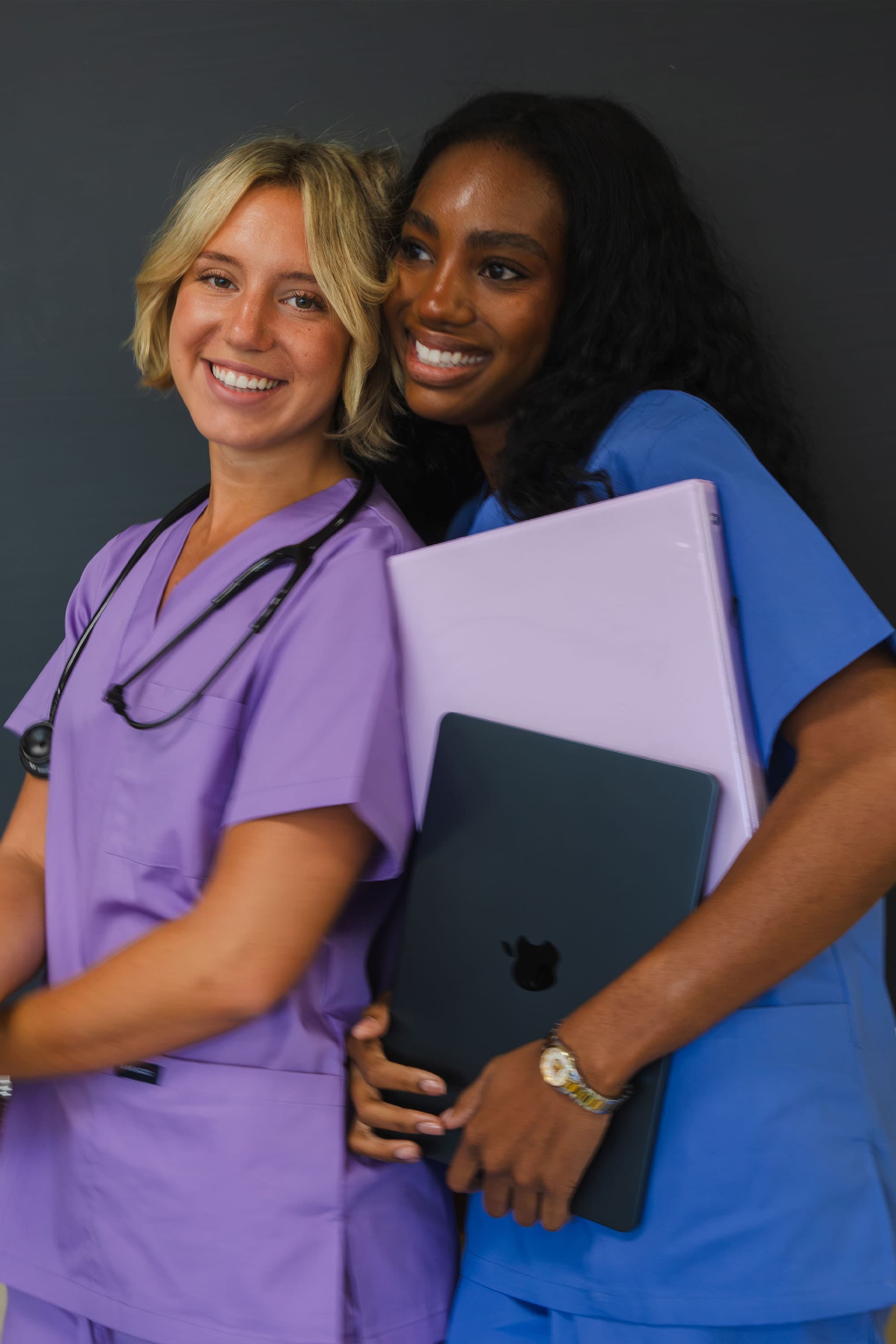 Two nursing students smiling with laptops